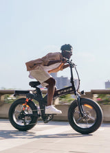 a man riding a black engwe x20 foldable electric bike on the road